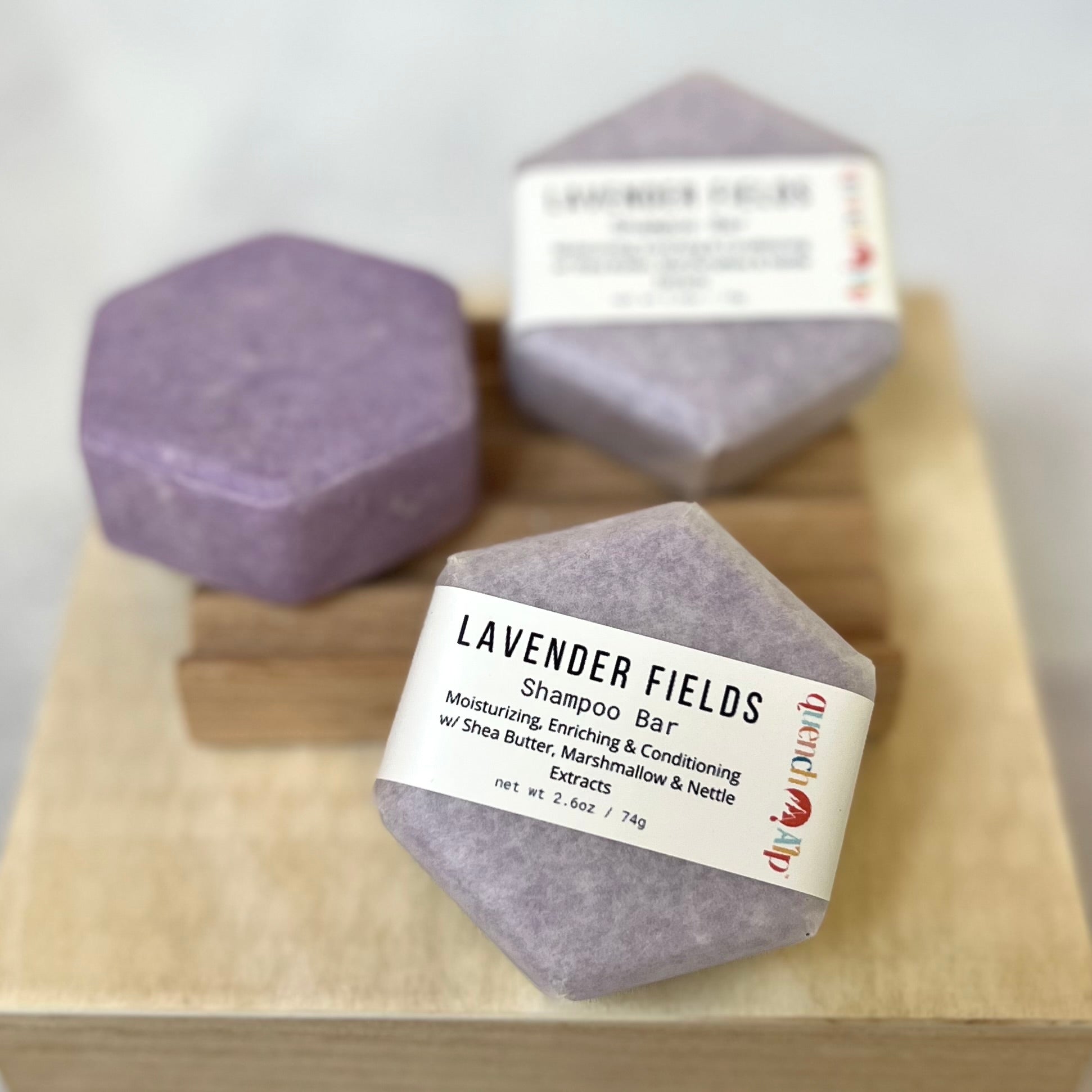 Lavender Fields shampoo bars on a wooden block with labels.